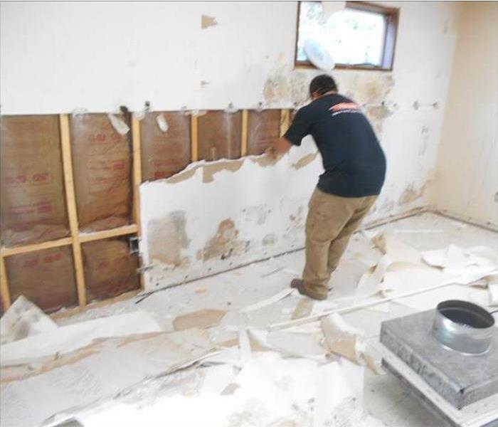 A picture of an employee demoing a basement due to mold.