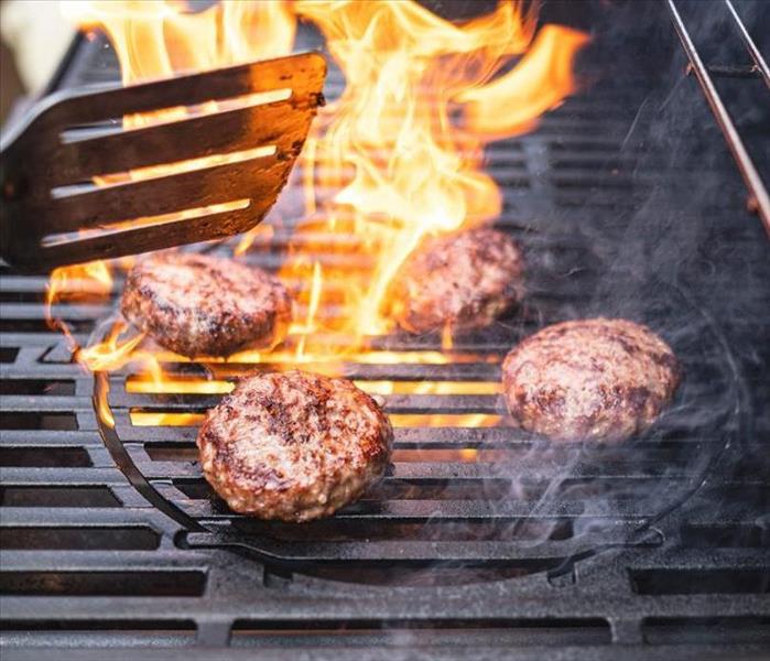 A picture of grilling burgers with flames. 