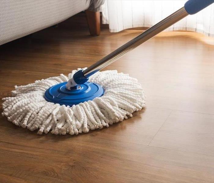 A picture of hardwood flooring getting clean by a mop.